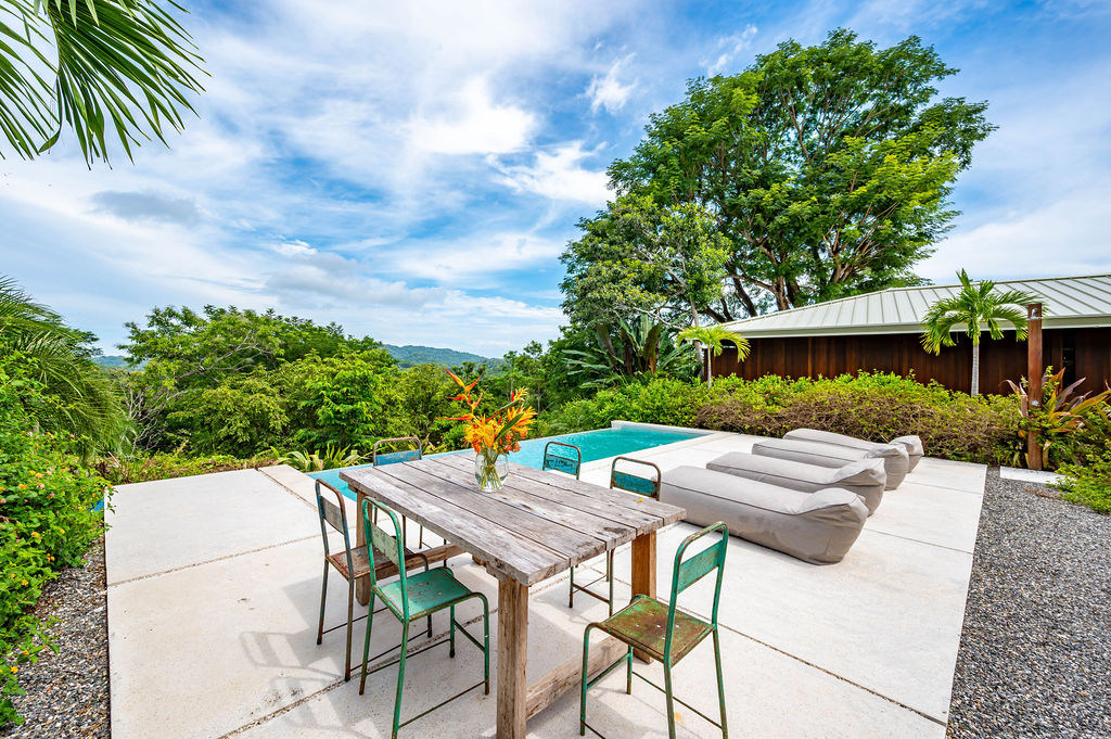 Outdoor dining table set on the pool deck above the jungle canopy