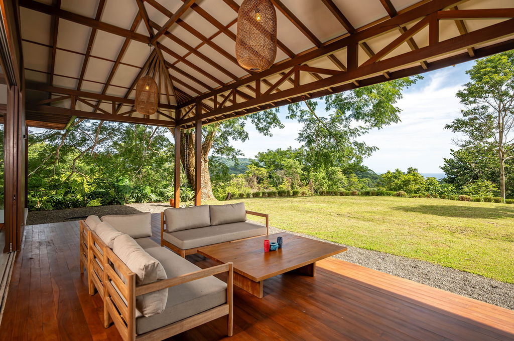 Covered terrace lounge with sofas looking toward the distant ocean